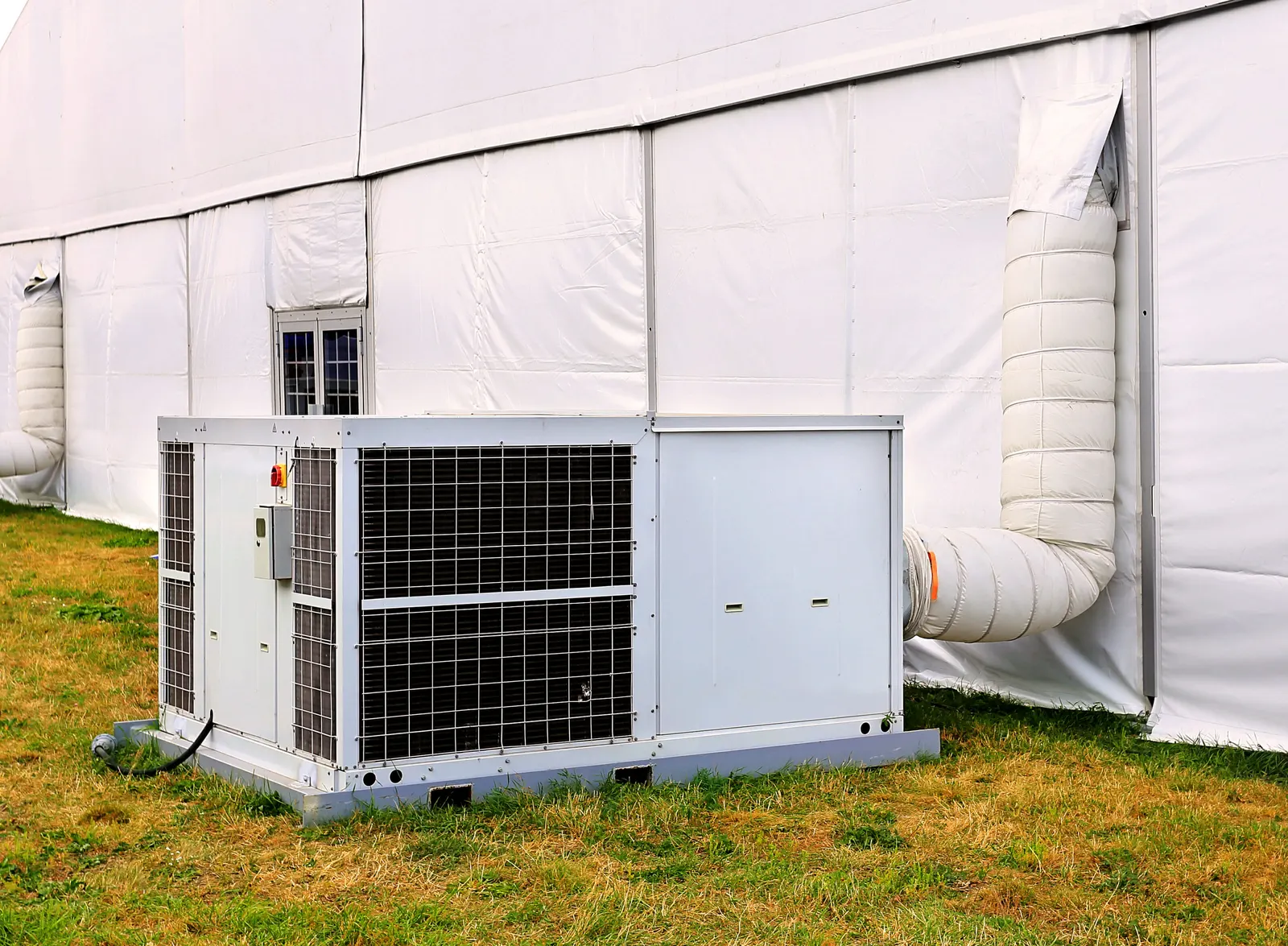 Weiße Zeltheizung vor Zelt mit Warmluftschlauch nach innen